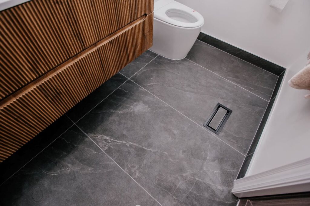 Charcoal slate look porcelain floor with matte black linear drain, fluted oak vanity and smart toilet in a Markham master bathroom