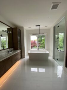 bathroom renovation toronto gta The modern master bathroom features a freestanding tub, a wall-mounted double vanity with a large mirror, and two ceiling-high cabinets on either side.