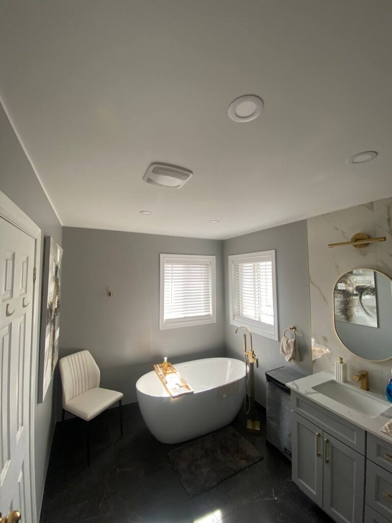 modern bathroom with white freestanding tub gray walls and gold fixtures