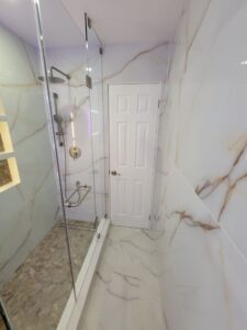 The floor features large format tiles, also mimicking white marble, but with deep, dark gray veins Thornhill