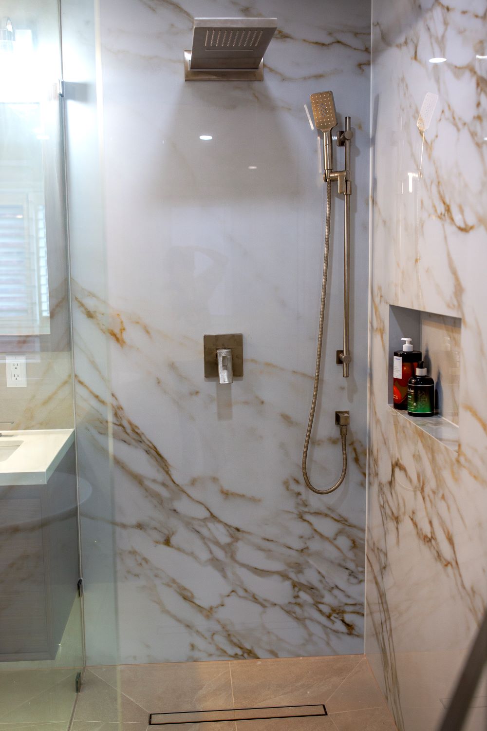 A luxurious concealed shower system (including a “tropical rain” overhead shower and a hand shower on a bar) in a brass finish