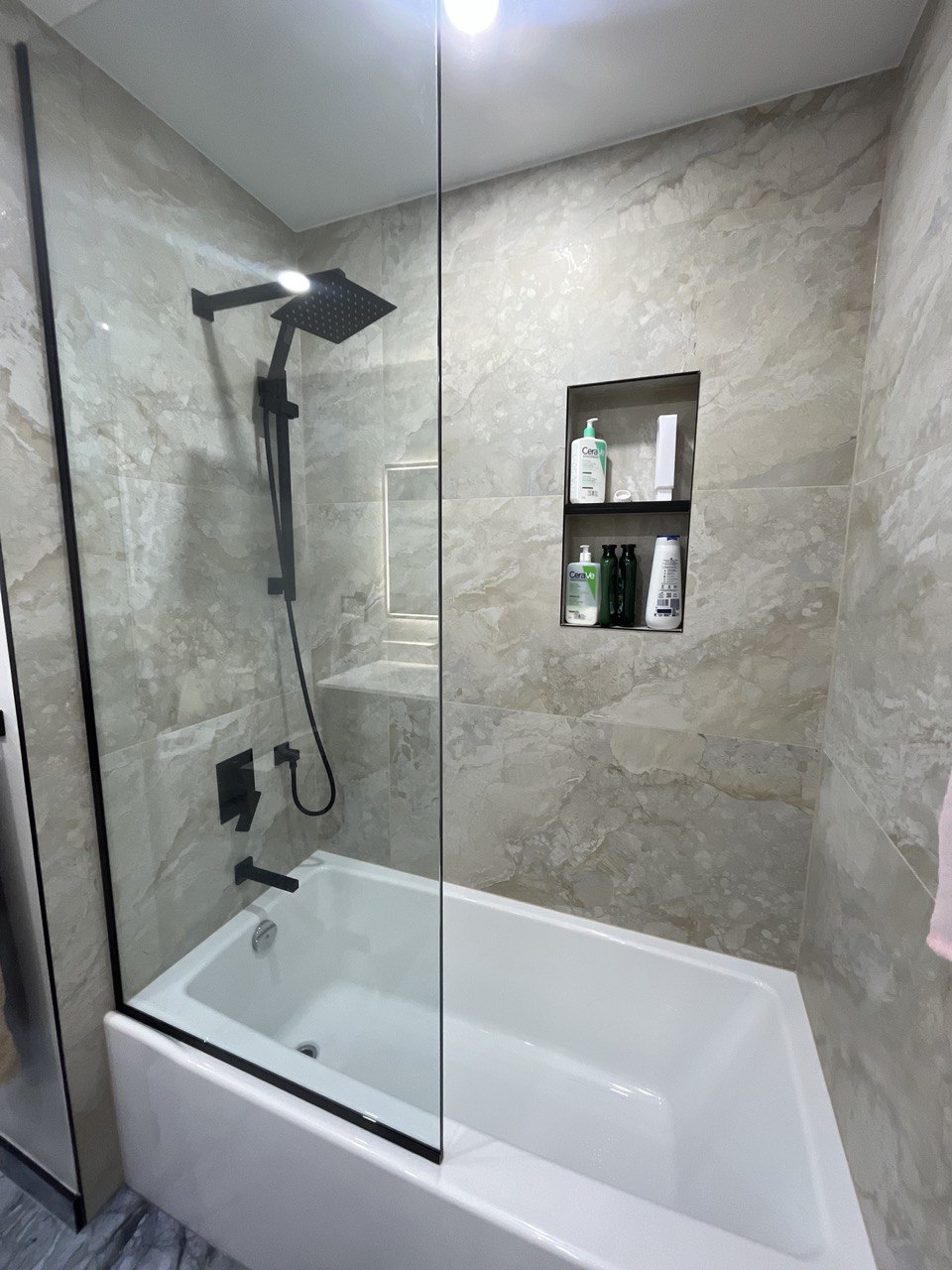 Elegant bathroom remodel with tub, beige stone look tiles, and matte black shower system Barrie
