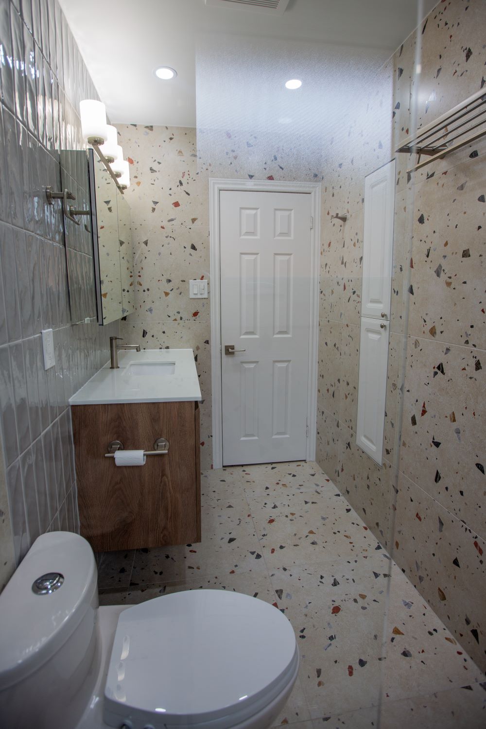 Modern bathroom remodel with terrazzo floor and walls, floating vanity, and wall mounted mirror Barrie