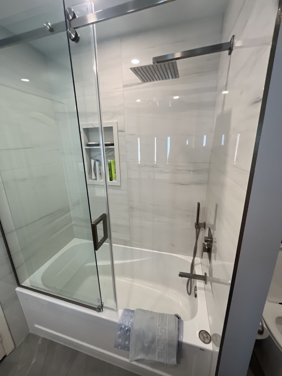 Modern bathroom renovation with tub and glass sliding doors, wall niche and rain shower head Barrie