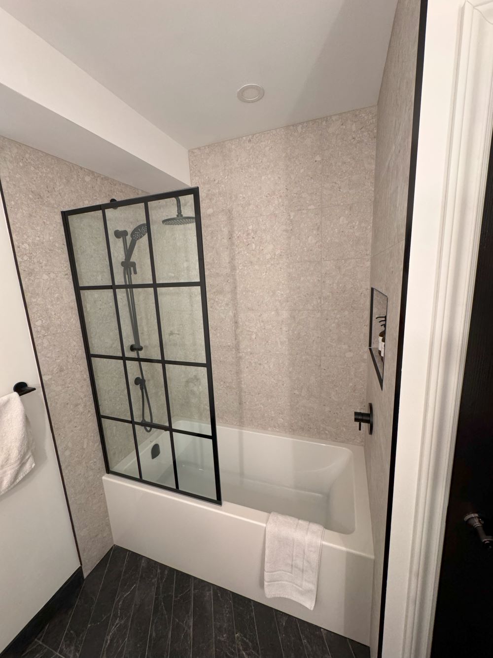 Modern bathroom with white bathtub, matte black fixtures, and a glass shower screen with black grid frame Barrie
