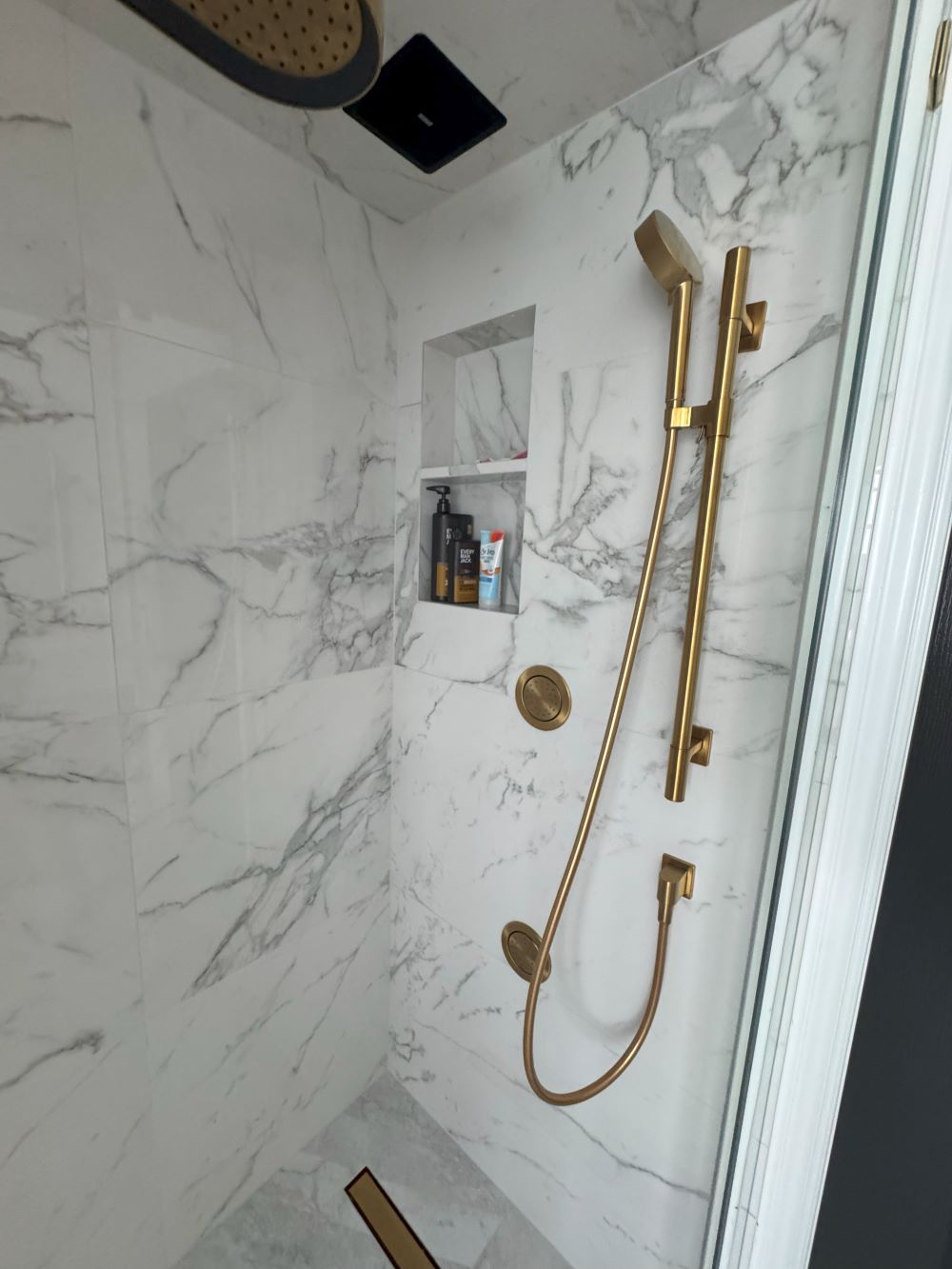 Tub to shower conversion. Shower niche with brass hand shower and marble wall tile Barrie