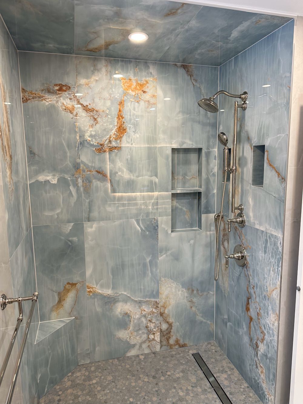 converting a bathtub into a shower. The walls inside the shower feature impressive large format tiles imitating blue grey onyxmarble with vibrant rust gold veining Barrie