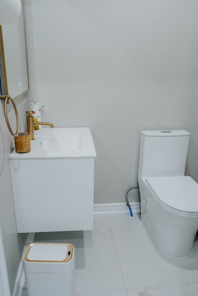 A complete view of the custom built powder room, showing the floating vanity, modern white toilet, and the seamless Calacatta Gold porcelain floor