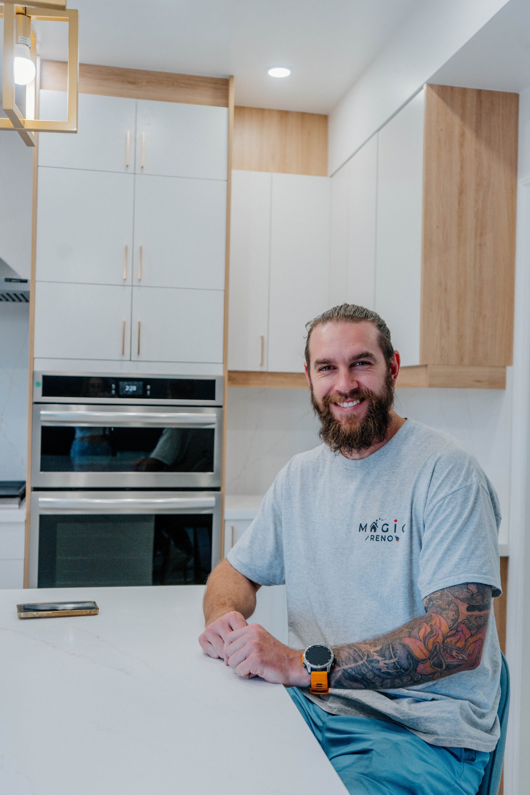 A member of the Magic Reno team smiling at the completed quartz island in the kitchen renovation project Pickering