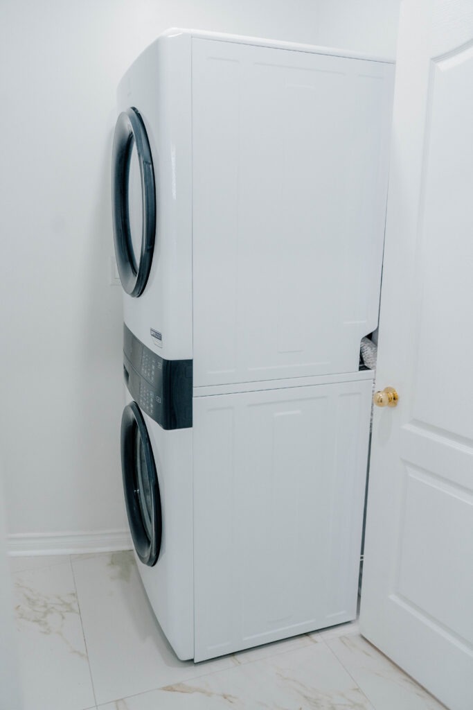 A modern, space saving stacked washer and dryer unit installed in the renovated laundry room