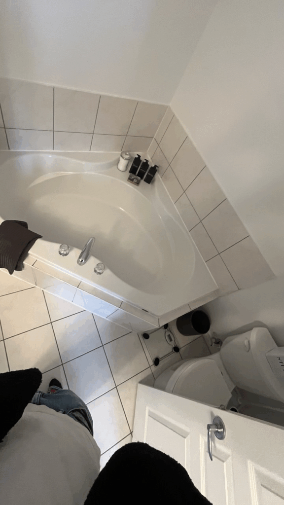 Before bathroom renovation photo. Outdated corner tub with beige tile and chrome hardware. Showing the original layout for this GTA bathroom renovation project