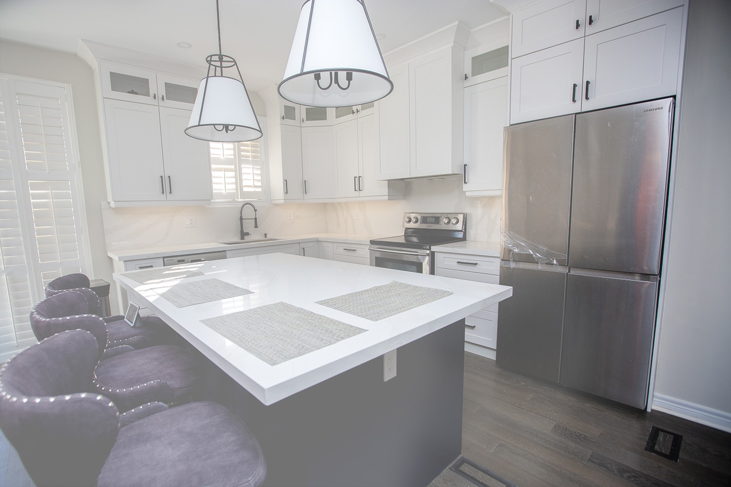 Kitchen renovation in Mississauga with white cabinets, dark blue island base, and a white quartz countertop