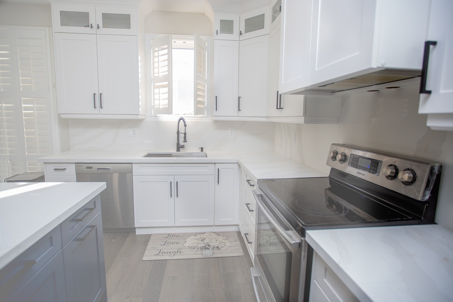 Clean white Shaker kitchen renovation in Brampton featuring a deep undermount sink, quartz countertops, and modern black faucet