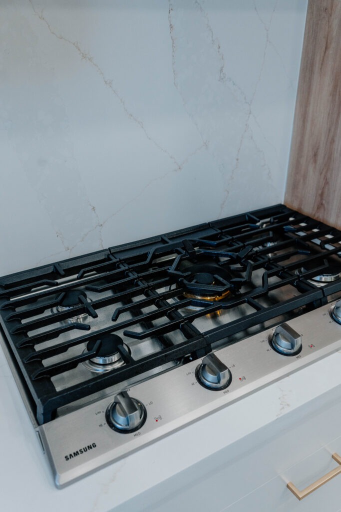 Close up shot of the Samsung stainless steel gas cooktop with five burners, installed in the quartz countertop