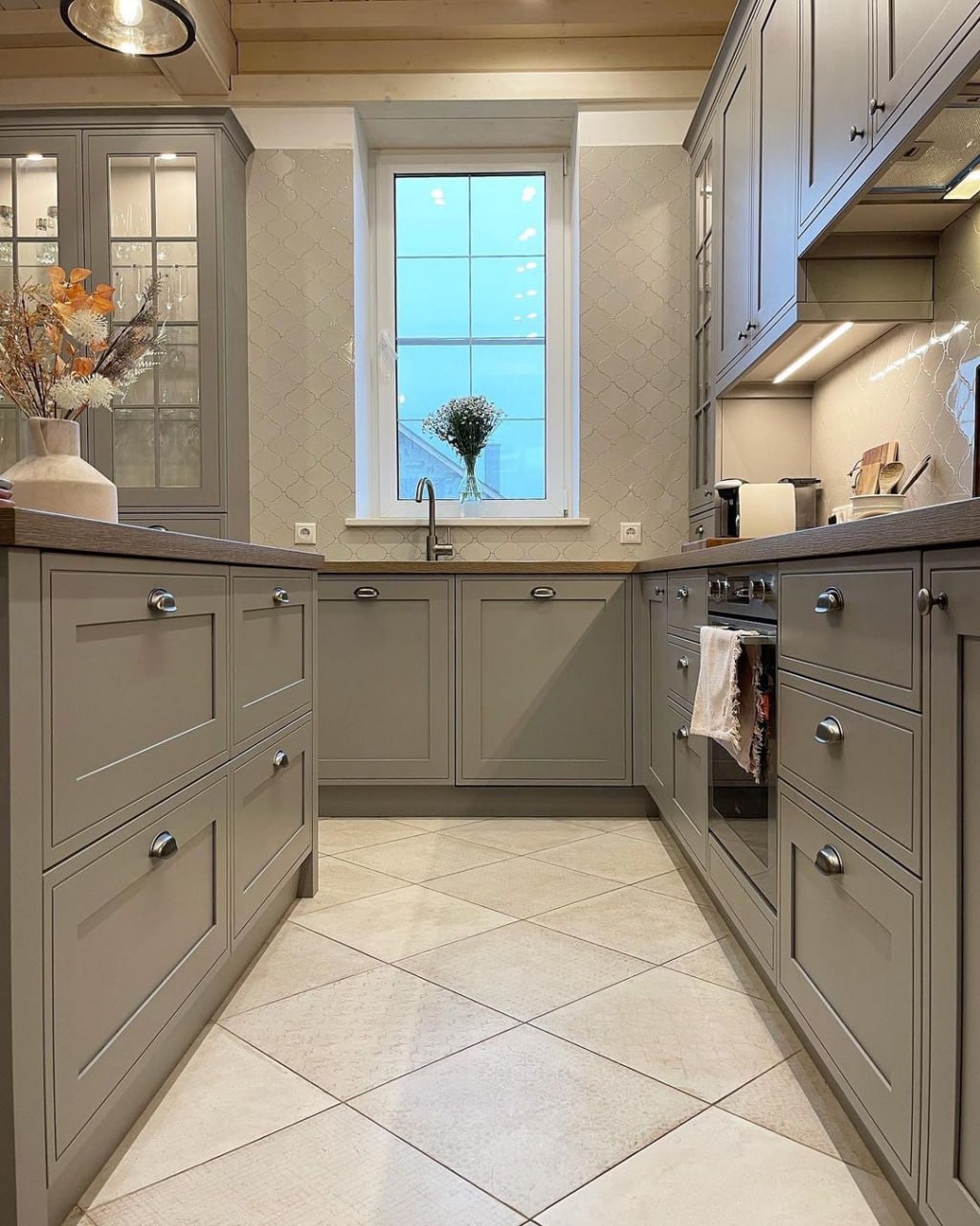 Cozy U shaped kitchen in a grey shaker style with wooden countertop accents and subtle tiled wallpaper around the window Pickering