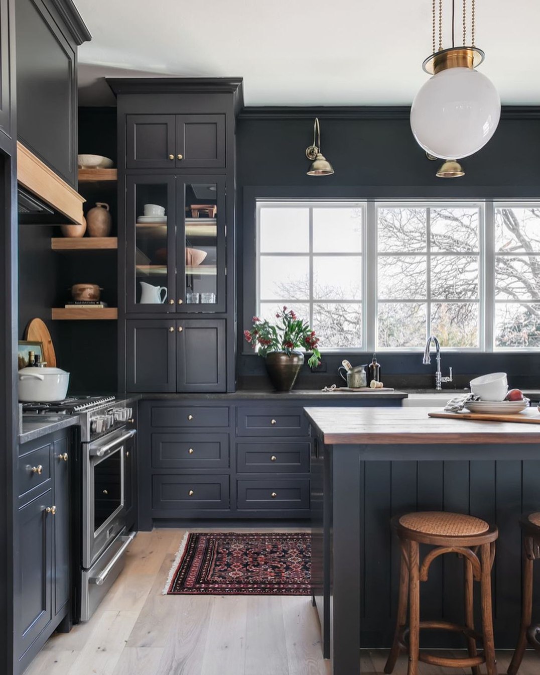 Dark navy blue traditional Shaker kitchen featuring a farmhouse sink, white globe pendant light, and black paneled appliances Pickering