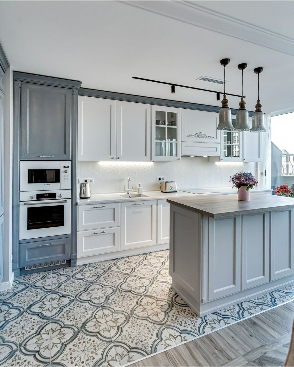 Frontal view of the U shaped kitchen area showing the main sink area, island, and contrasting two tone gray and white cabinetry