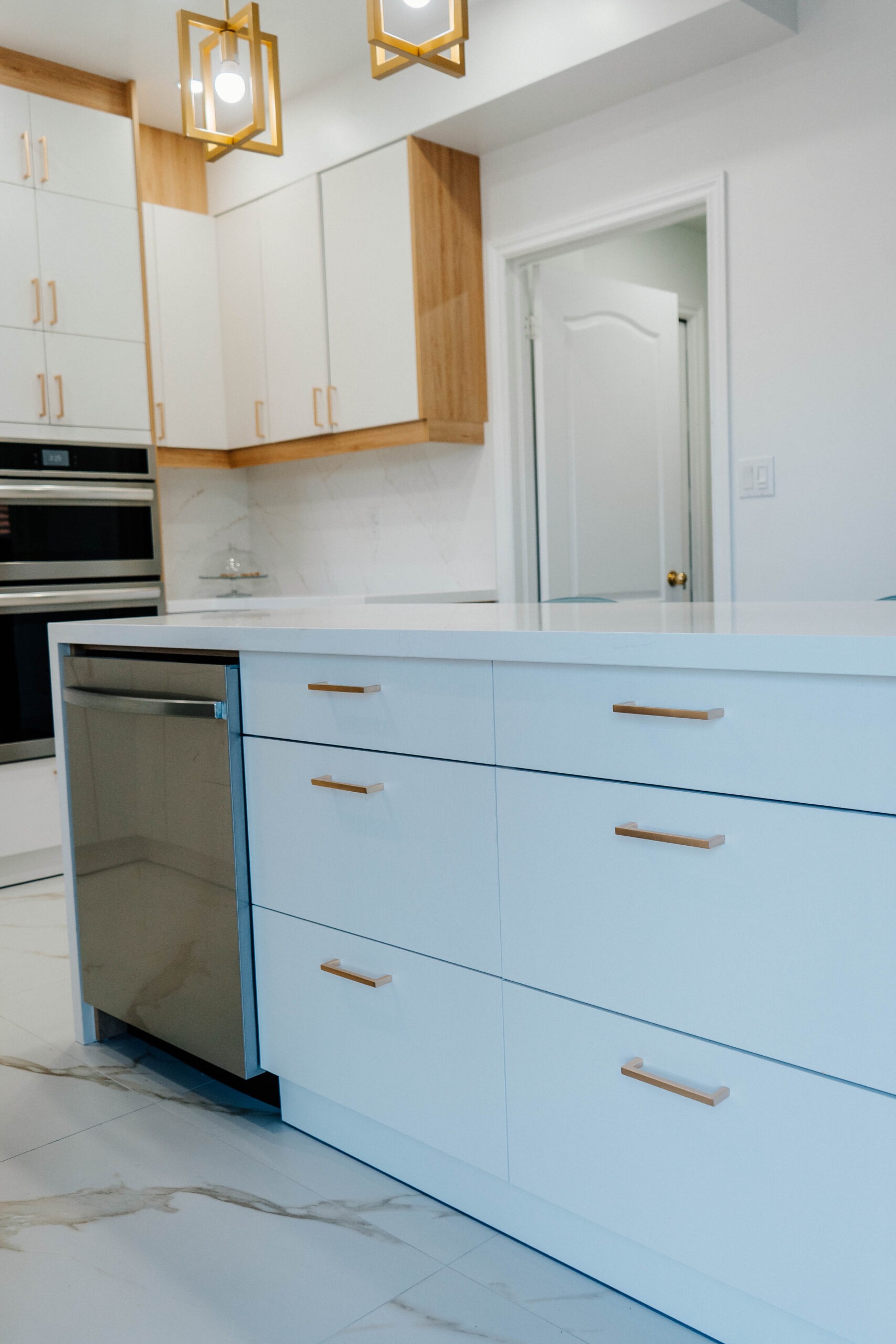Functional and stylish kitchen island with Matte White flat panel drawers, gold hardware, and an integrated dishwasher Pickering