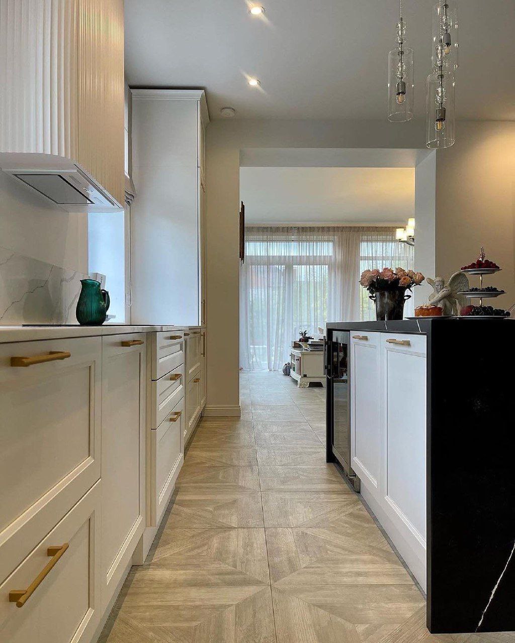 Hallway view of the galley style kitchen looking into the dining room, showing the dark waterfall island and light wood look tiled flooring Pickering