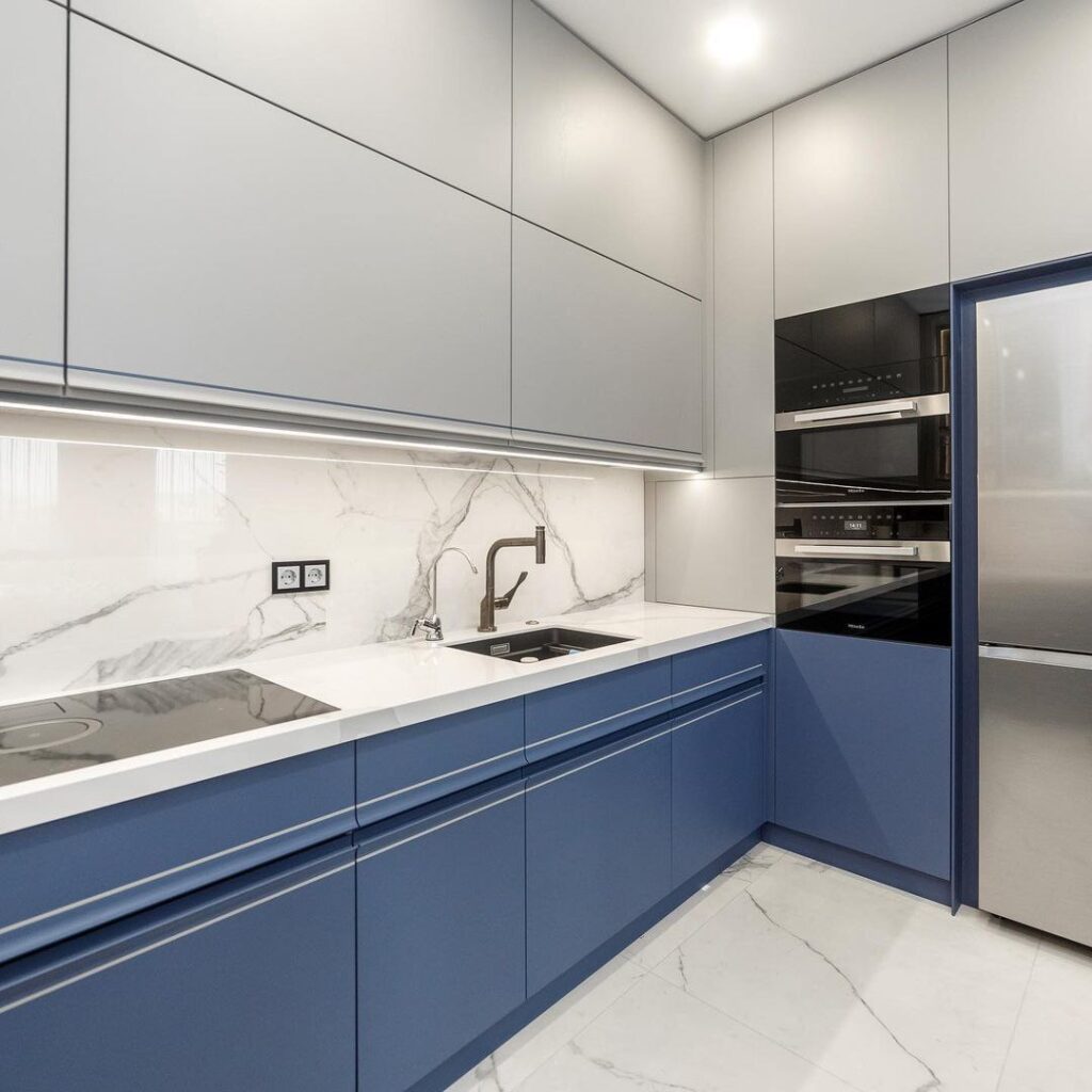 Kitchen remodel in Brampton Close up of the kitchen corner showing integrated double ovens, modern black faucet, and sleek grey upper cabinets above blue base cabinets