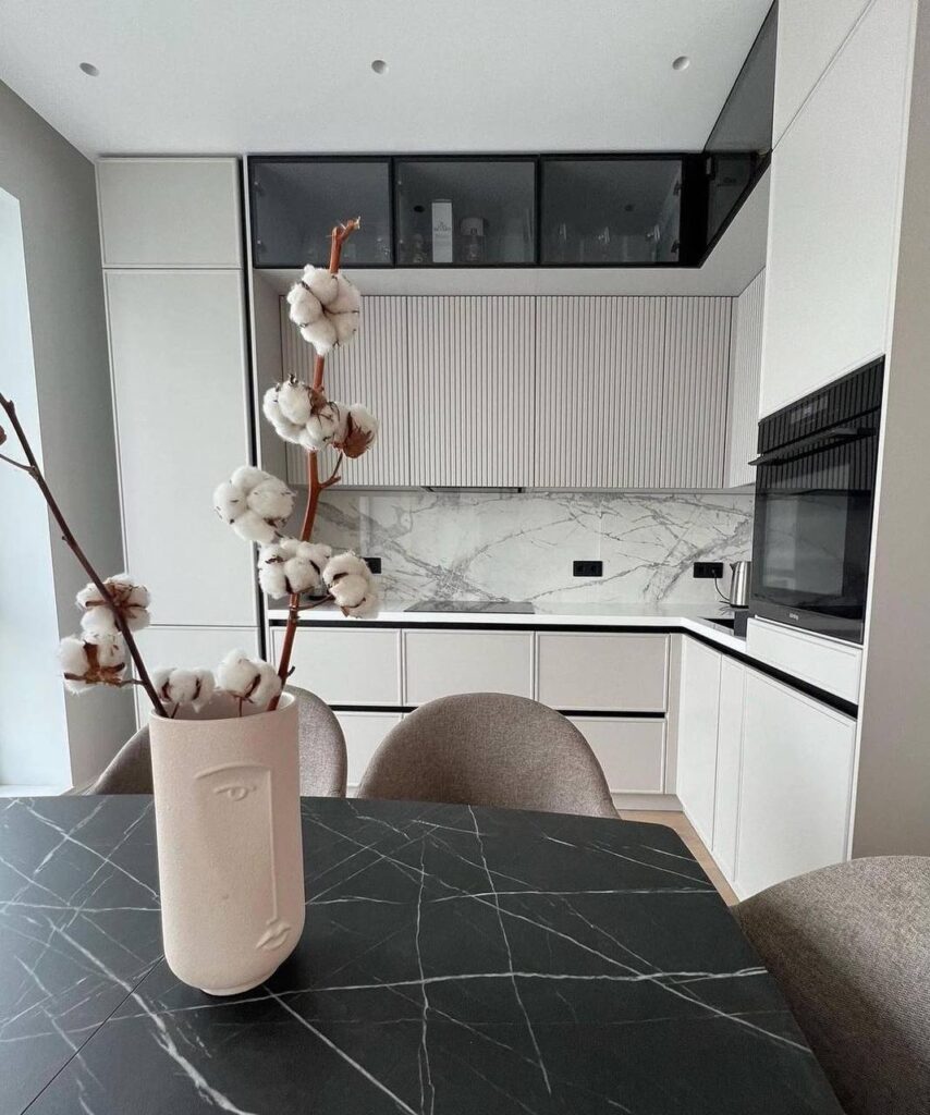 Kitchen remodel Mississauga Light minimalist kitchen design with white fluted cabinets, marble backsplash, and a black veined marble dining table