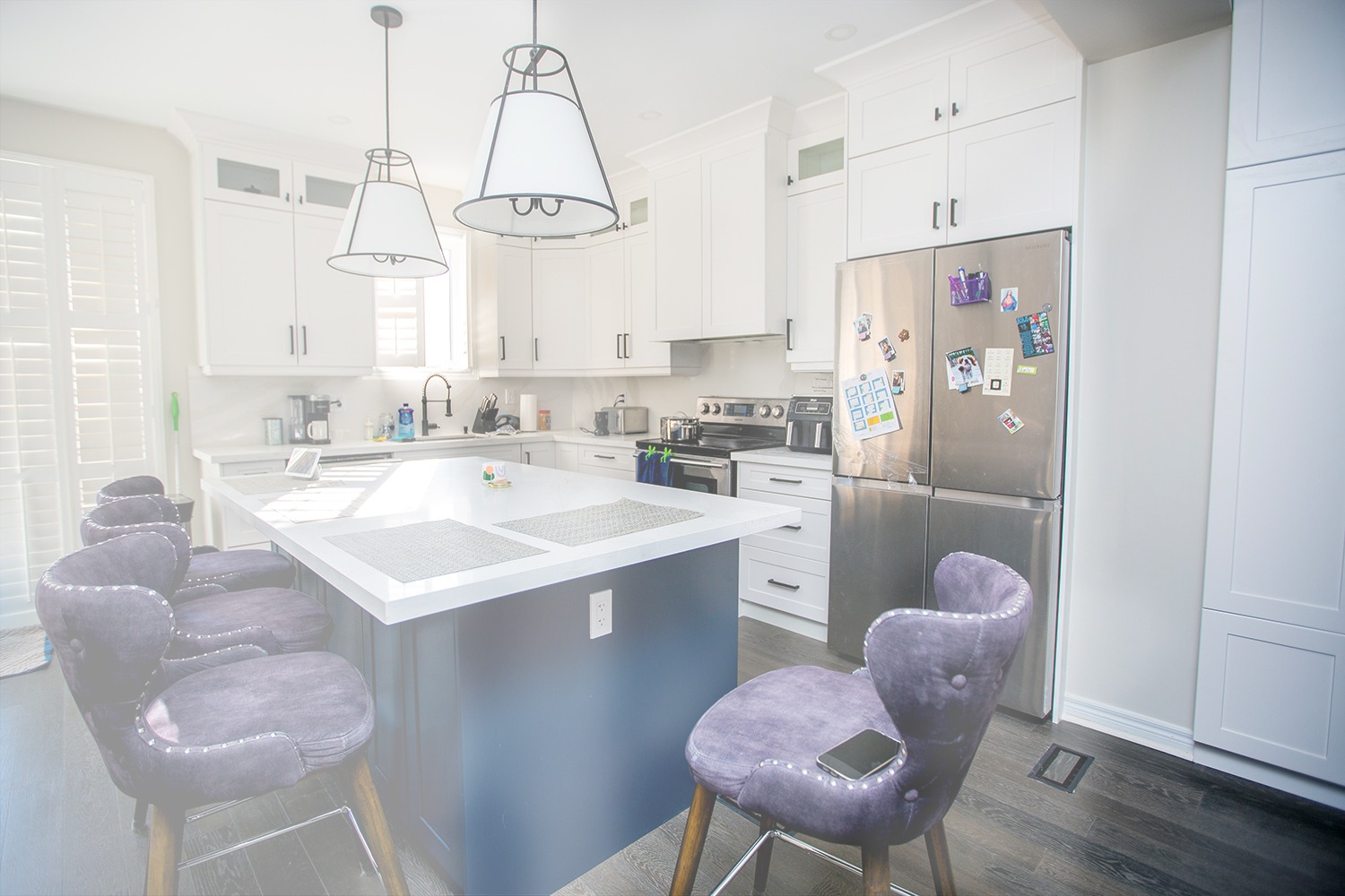 Modern farmhouse kitchen renovation in Markham featuring white shaker cabinets, a large dark grey island with white quartz countertop, and stainless steel appliances