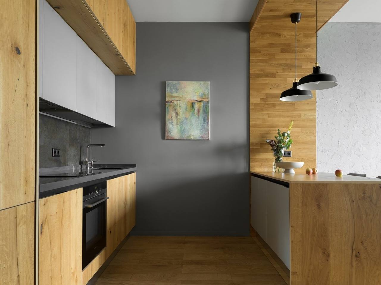 Sleek modern galley kitchen with wood base cabinets, matte gray walls, minimalist faucet, and a contemporary painting Pickering