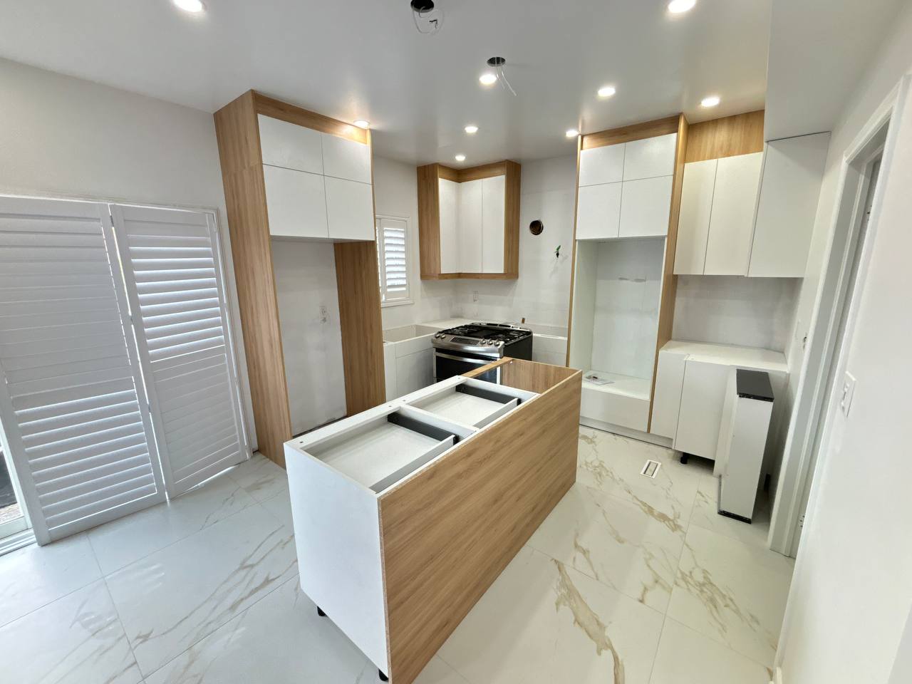 The kitchen island base and surrounding two tone cabinets are in place during the final stages of the Thornhill renovation, awaiting measurement for countertops Pickering