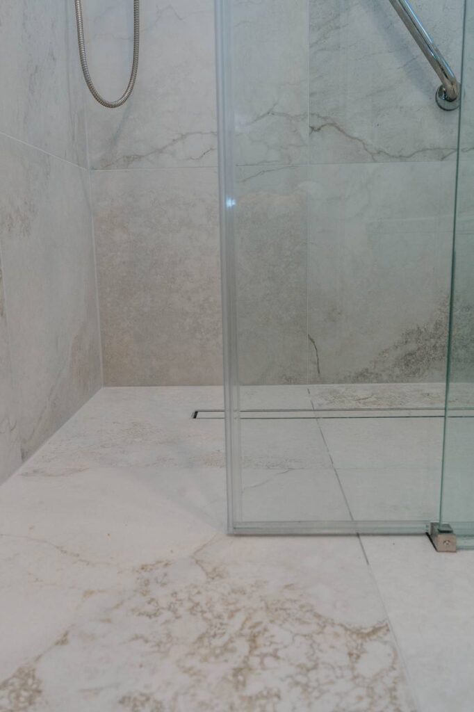 Curbless walk in shower with linear drain and large format marble look porcelain tile