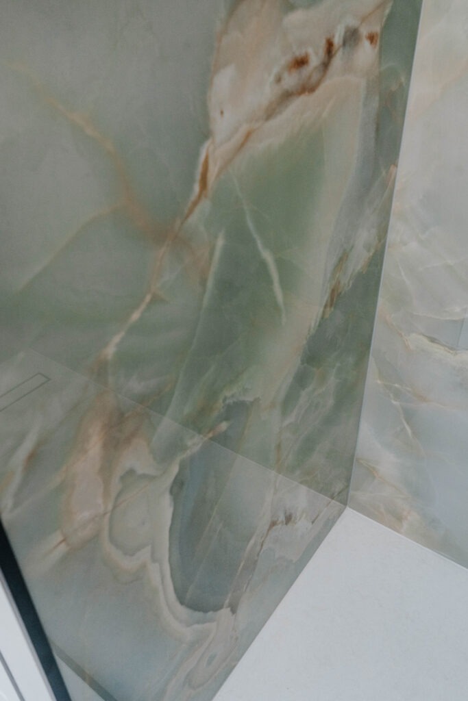 Detail of large format porcelain tile corner installation showing precision joint and waterproof epoxy grout