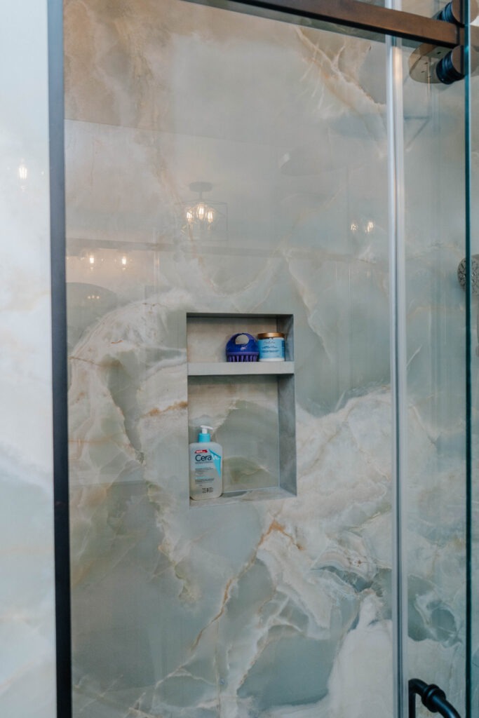 Luxury walk in shower featuring floor to ceiling azure onyx slabs and custom sliding glass door system