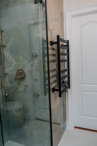 (Towel Warmer) Matte black electric towel warmer mounted on seamless porcelain slab walls