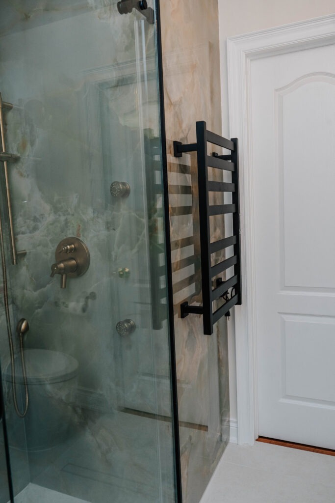 (Towel Warmer) Matte black electric towel warmer mounted on seamless porcelain slab walls