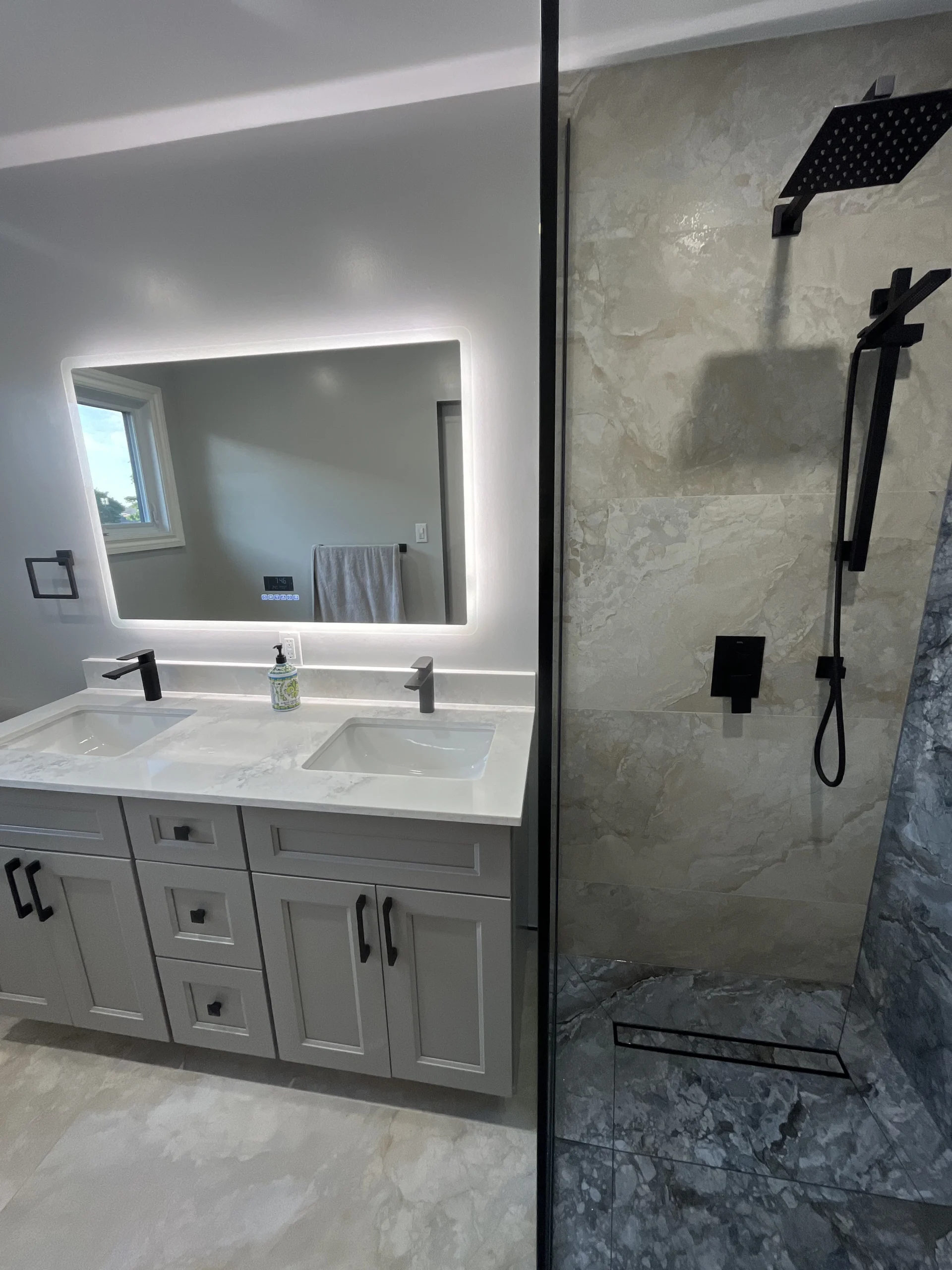 Light grey floating vanity with LED backlit mirror in a warm beige tiled bathroom