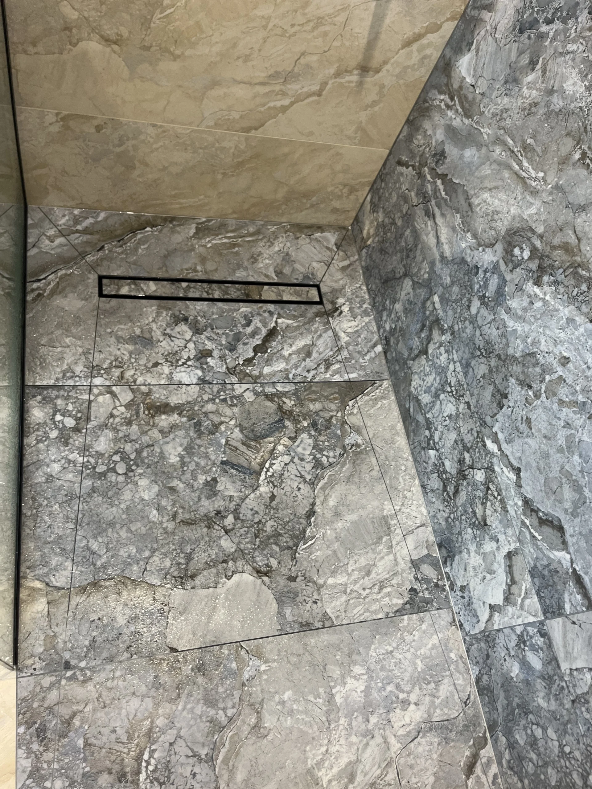 Tile insert linear drain in a shower with blue and grey marble effect tiles