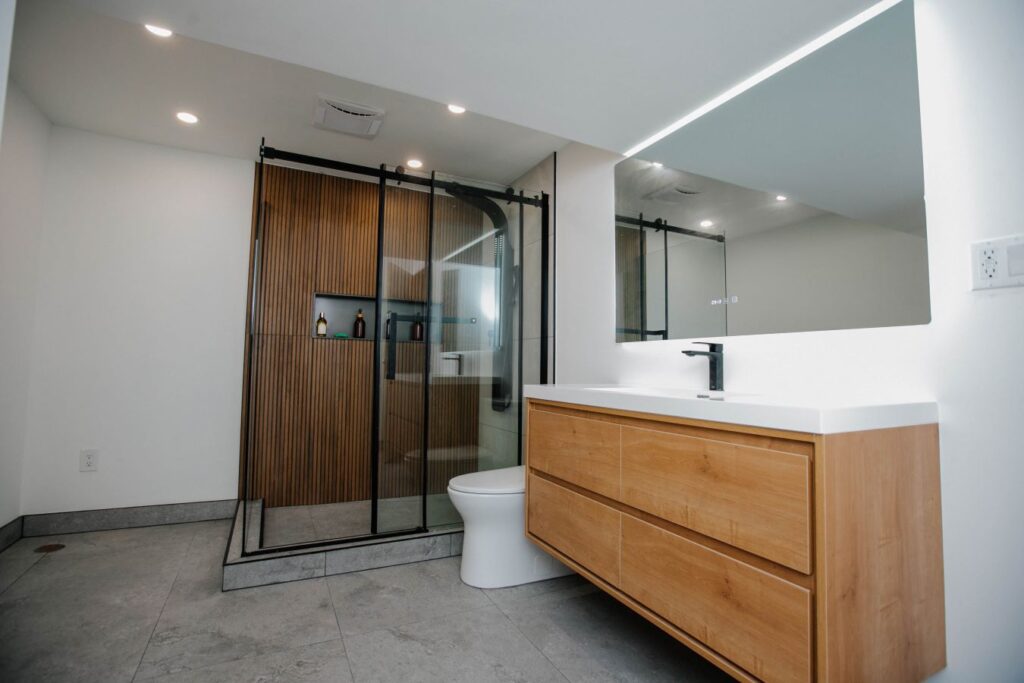 Wide angle view of the completed bathroom renovation highlighting the contrast between the wood accents and gray stone tiles