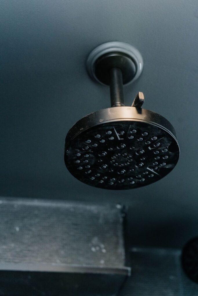 Ceiling mounted matte black rain shower head installed in a drop ceiling