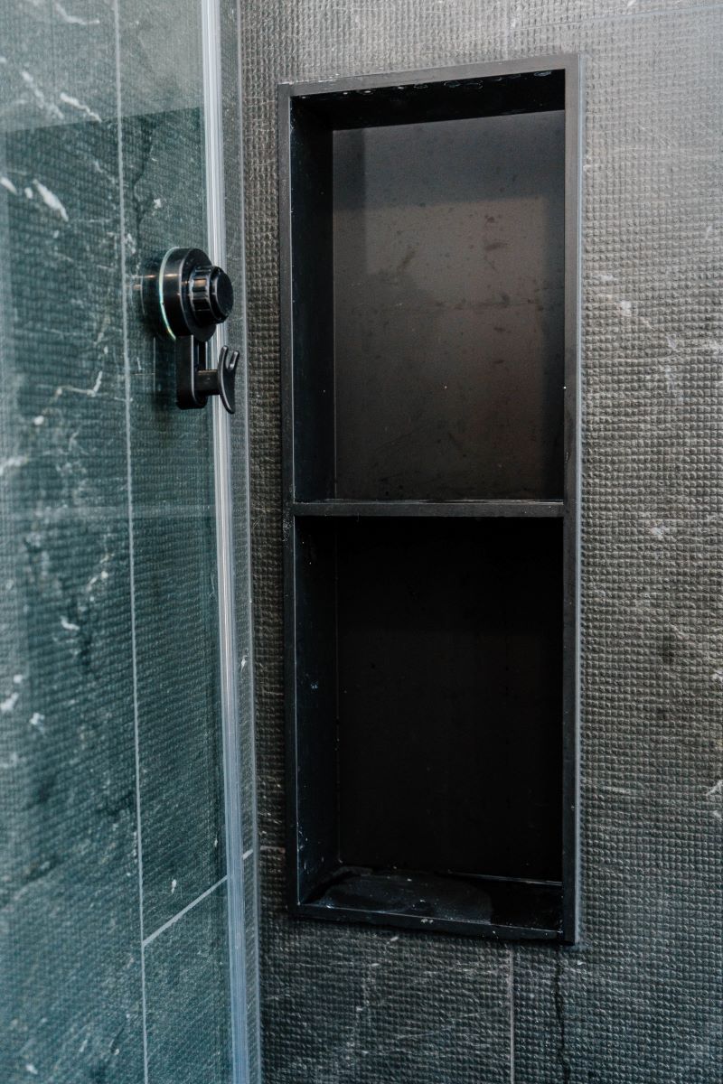 Custom built in vertical tiled shower niche with shelves, set into dark grey textured porcelain walls Vaughan