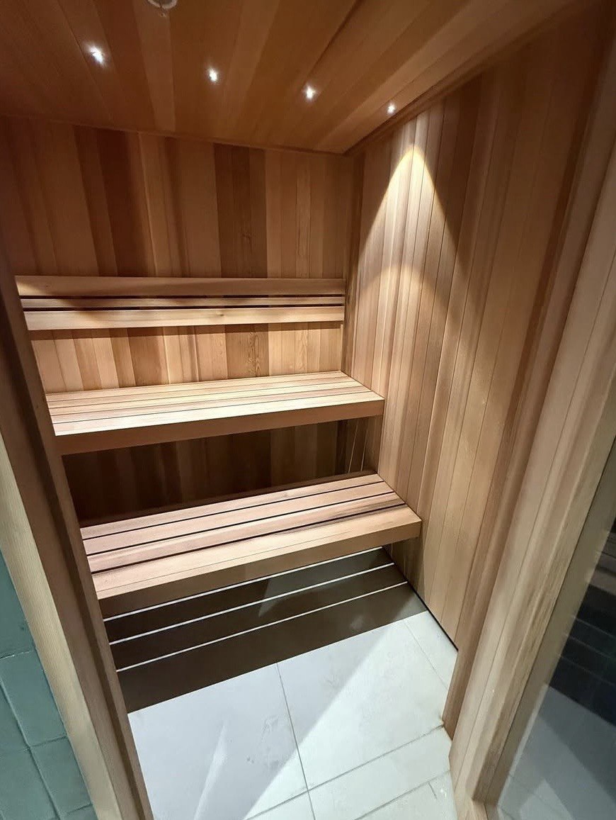 Custom wellness sauna construction in GTA with tiered cedar benches and recessed lighting