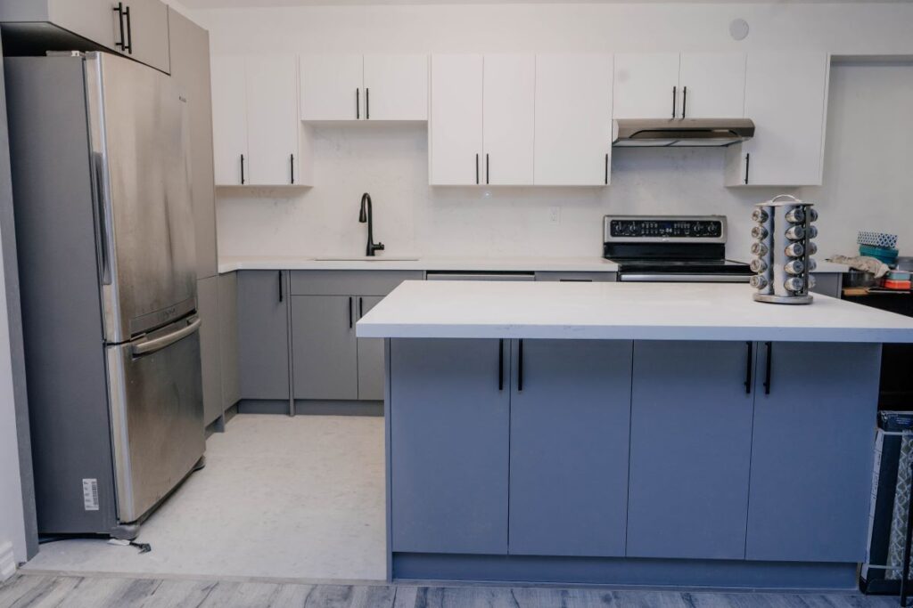 Front view of a condo kitchen remodel with two tone cabinetry, quartz countertops, and a functional island workspace