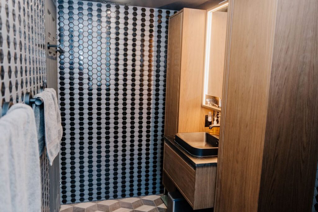 Full view of the vanity area featuring a tall wood cabinet, vessel sink, and a black and white hexagon mosaic accent wall