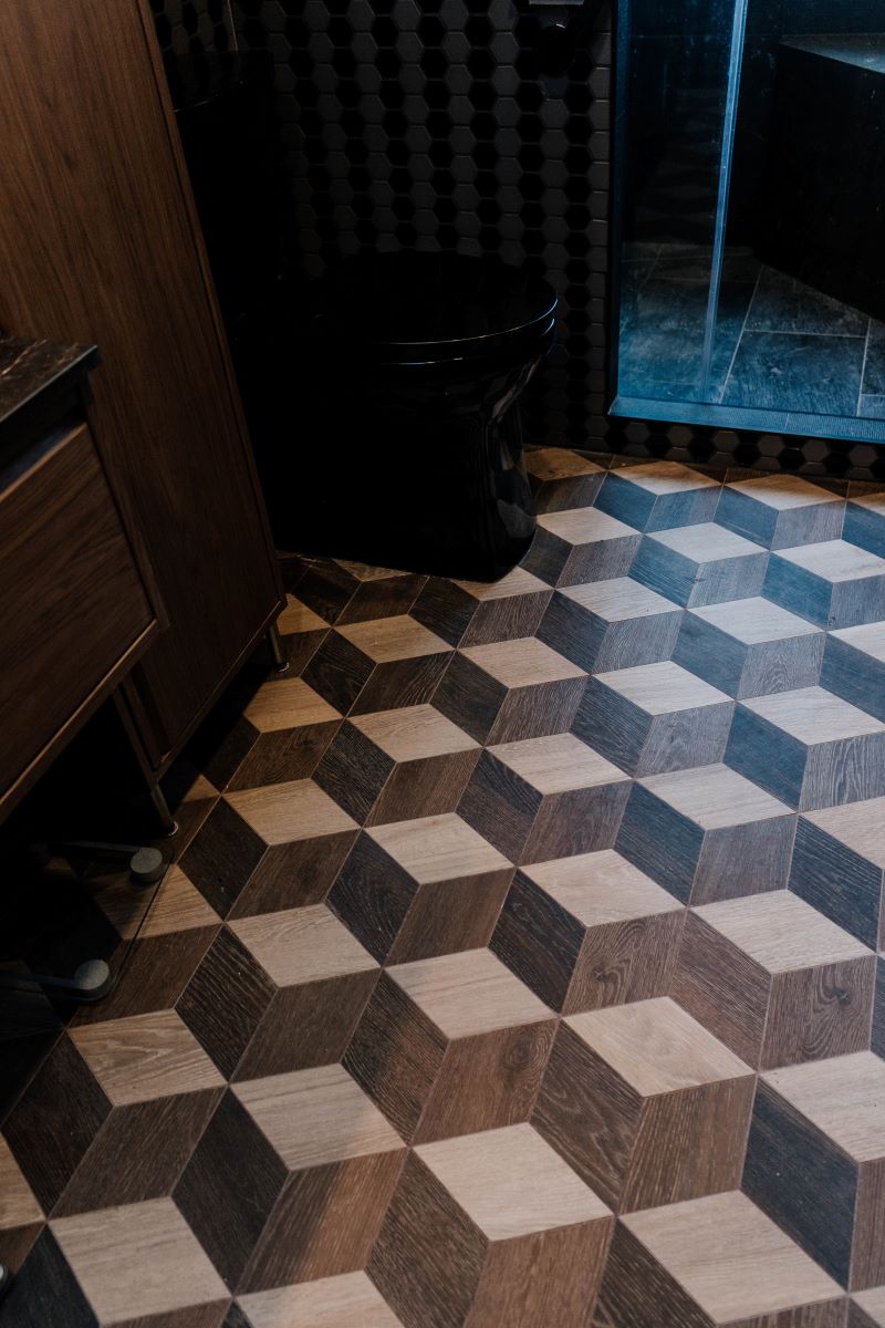 Geometric woodgrain porcelain floor tiles laid in a 3D cube pattern next to a black toilet Vaughan