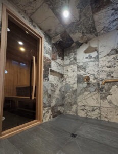 High end bathroom featuring a tiled steam shower installed next to a custom home sauna