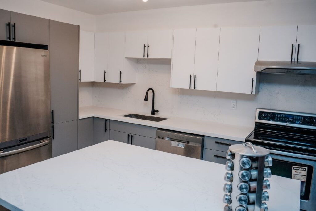 Modern kitchen design showing the contrast between grey base cabinets and white upper cabinets with a large central island