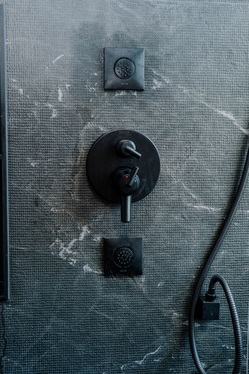 Modern matte black shower valve and body jet controls mounted on dark grey slate look porcelain tiles Vaughan