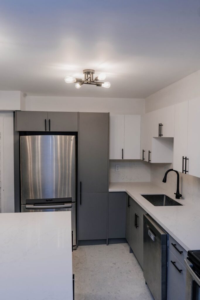Vertical view of the kitchen highlighting the tall grey pantry cabinet next to the refrigerator and modern ceiling light fixture