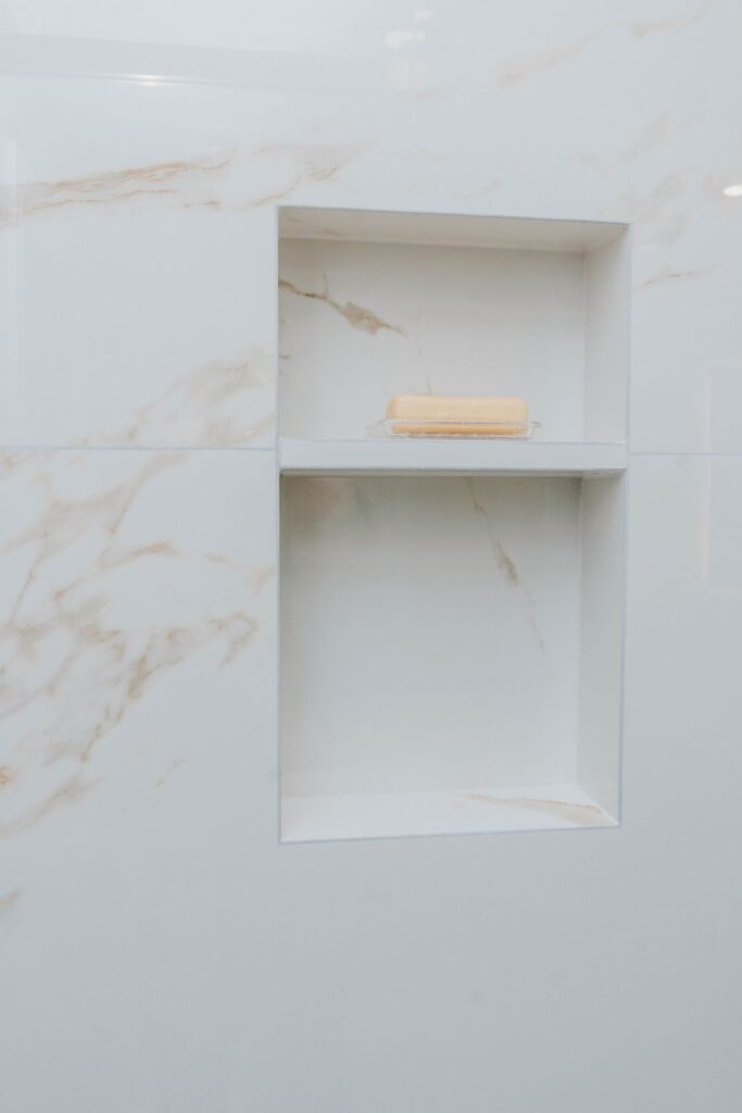 Built in tiled shower niche with white marble porcelain tile and a bar of soap