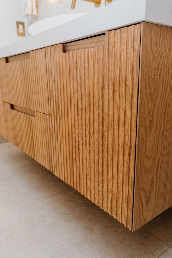 Close up detail of the fluted (ribbed) wood texture on the custom bathroom vanity drawers