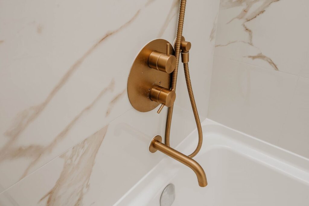 Close up of brushed gold tub filler and handheld shower attachment