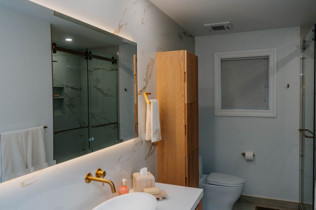 Custom floor to ceiling fluted white oak linen cabinet installed next to a renovated shower
